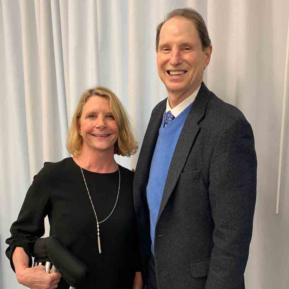 Kristin Quinlan stands next to Oregon Senator Ron Wyden. The two are posing for a picture and smiling.