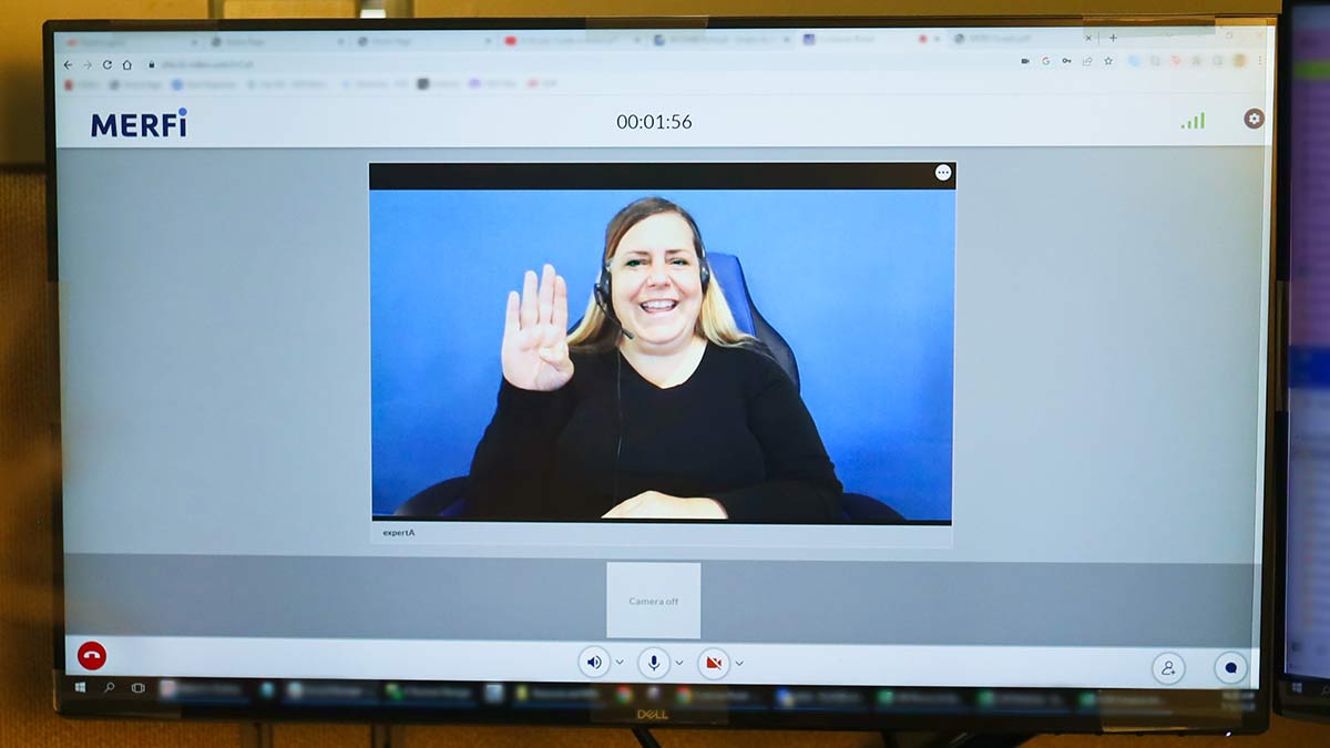 A smiling ASL interpreter works with a client on the CLI MERFi video interpreting platform.