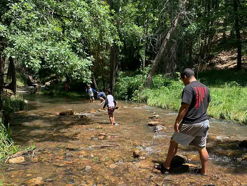 CLI employee Aaron walks in the river with children.