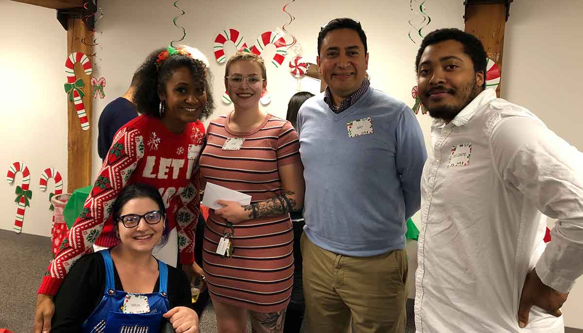 Five people including Art who work at CLI posing for a picture at a holiday gathering.