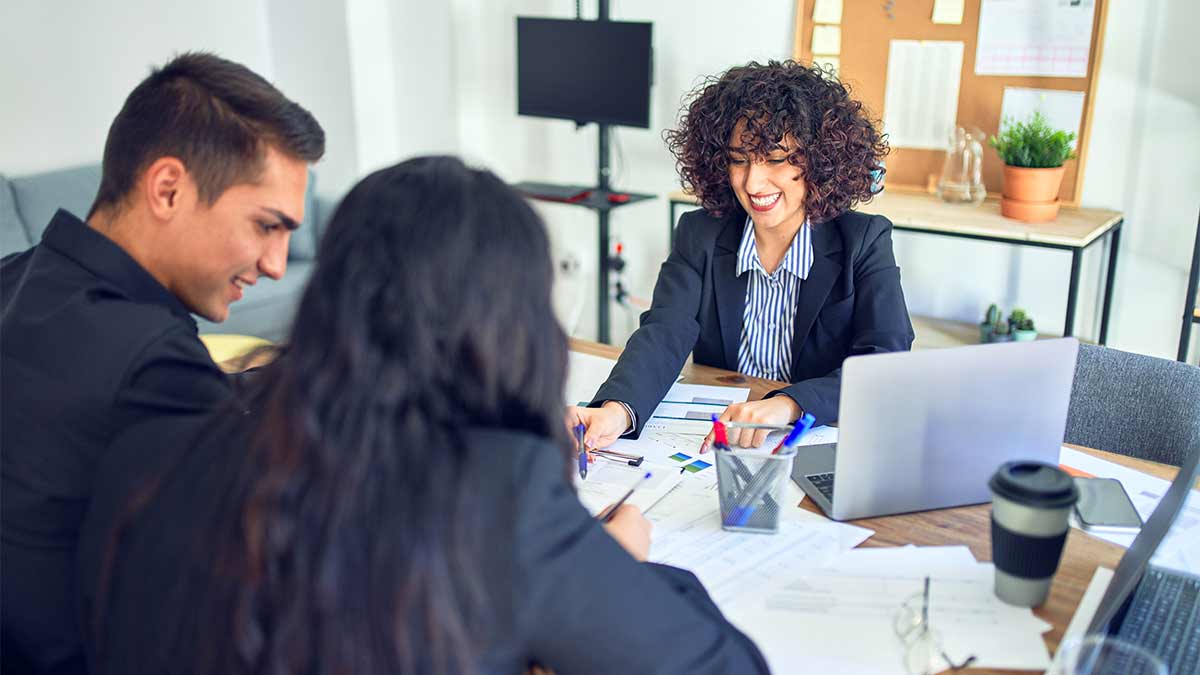 A loan officer signs two new clients with the help of an interpreter.