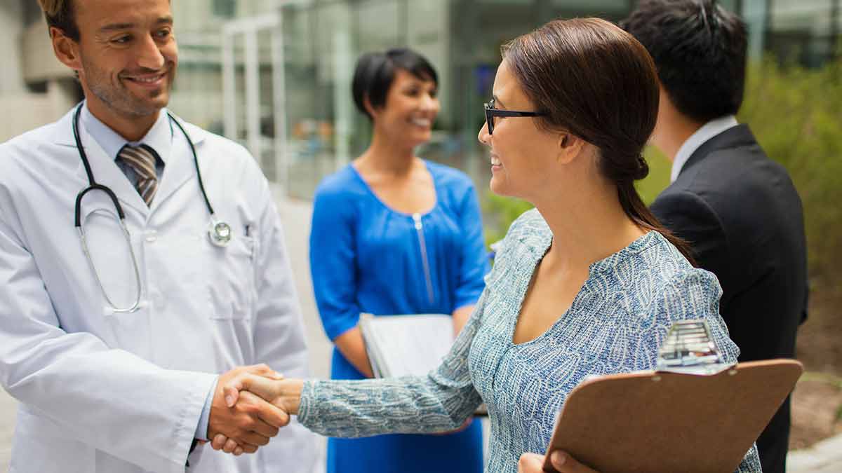 A doctor who supports a medical interpreter's well-being shakes the interpreter's hand.