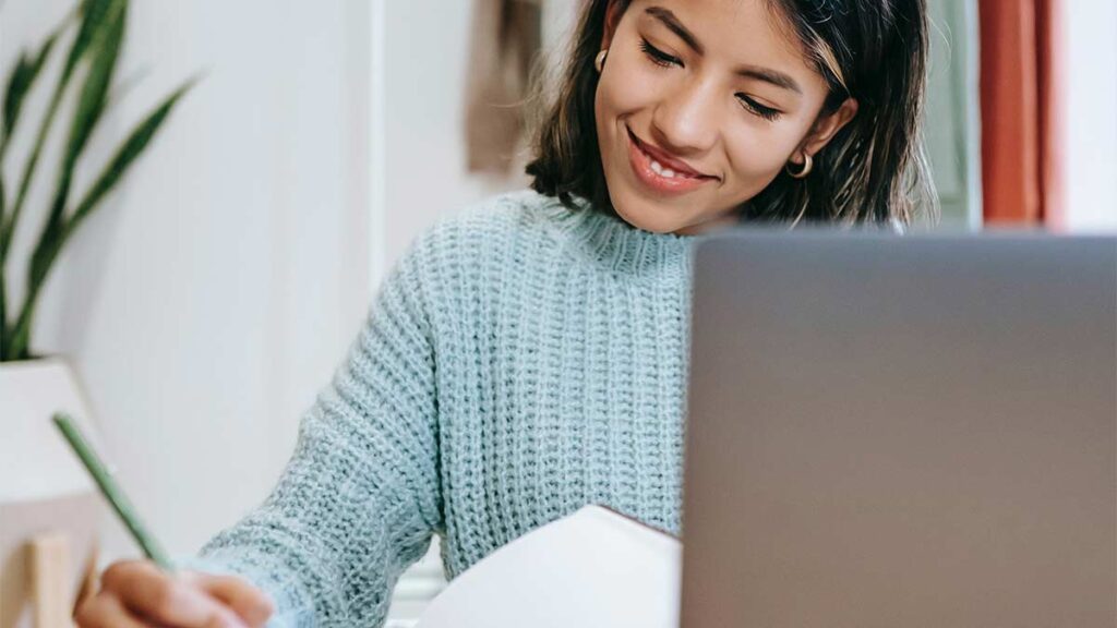 A translator works with a smile at a laptop.