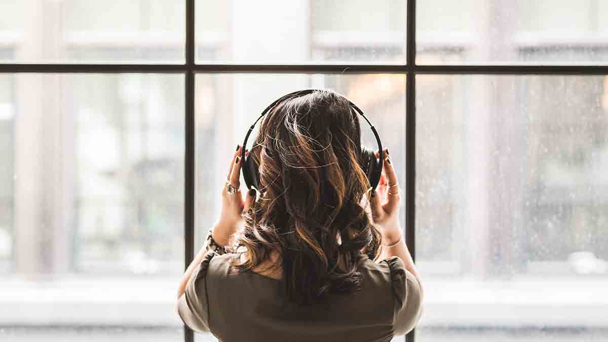 Female VRI ASL interpreter holding headphones and facing a window