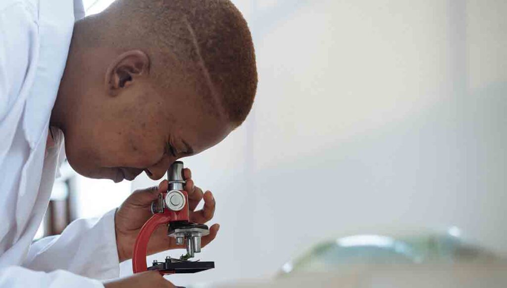 Female provider looking through a microscope at the details of a specimen. 