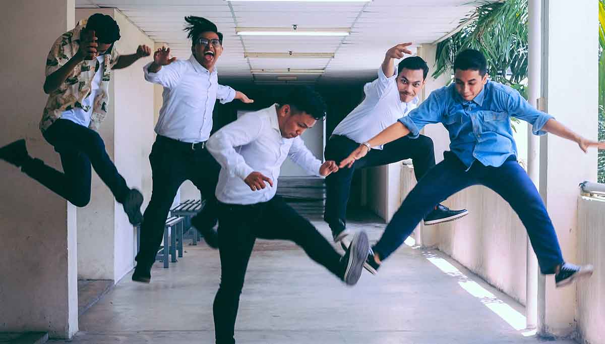 Five men jumping with excitement in a corridor over making their New Year’s resolution getting their medical interpreter certifications.