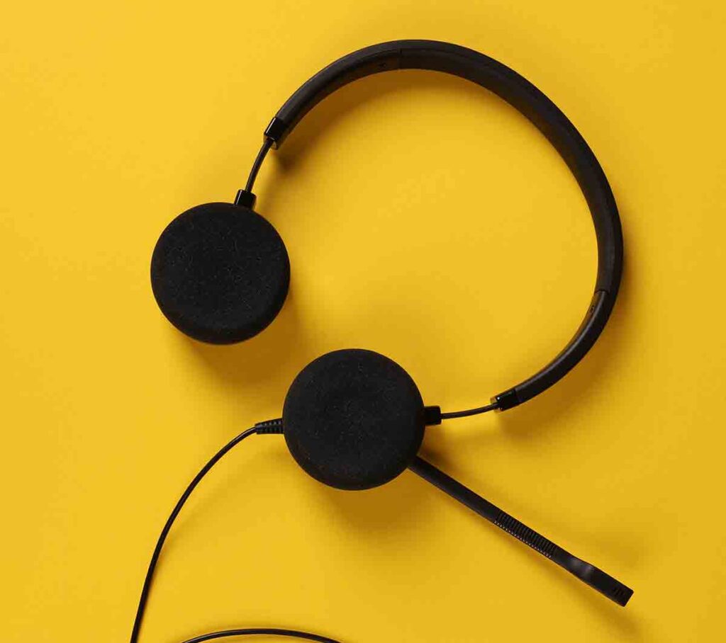 A headset that a video remote interpreter would use lying against a yellow background.