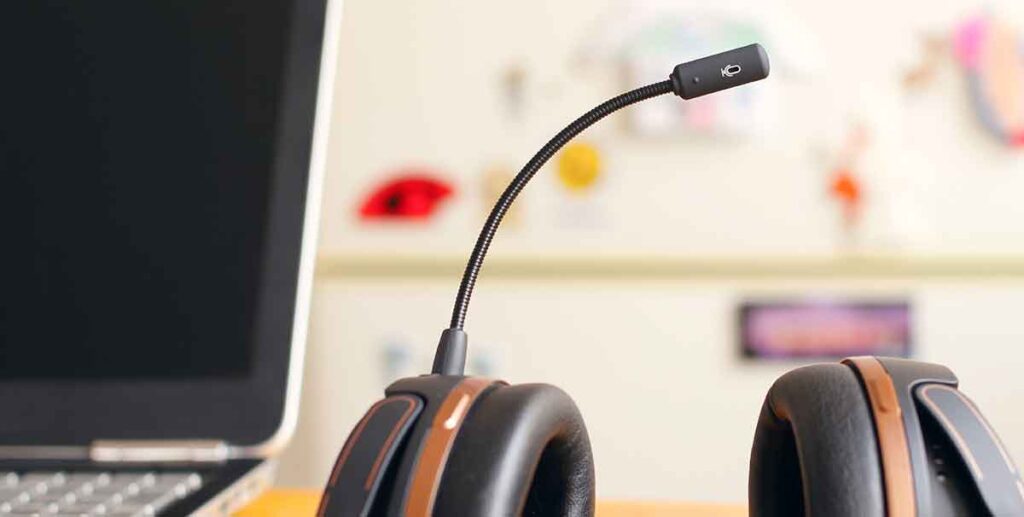 Laptop and headset with microphone sitting on a table. 