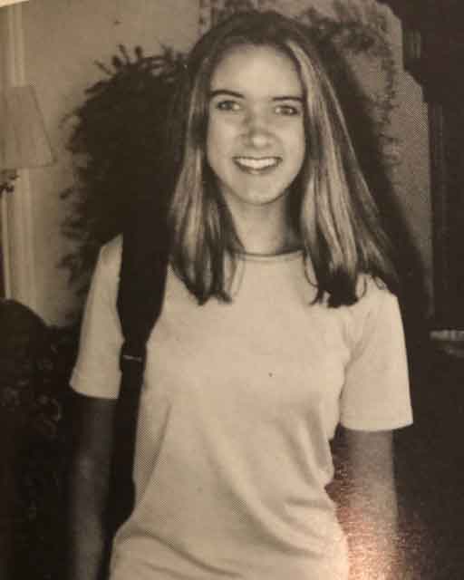 Jen with a backpack on her shoulder smiling on her first day of high school.