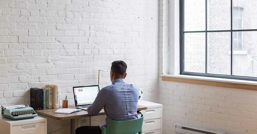 Male interpreter sitting at a desk on his laptop working remotely