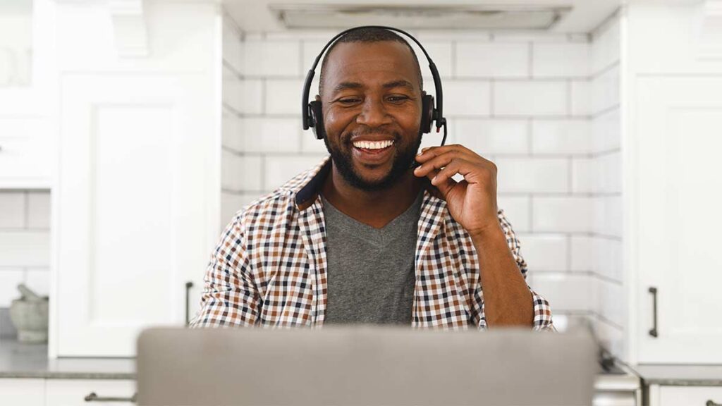 An experienced video remote interpreter smiles on a video call at their desk.