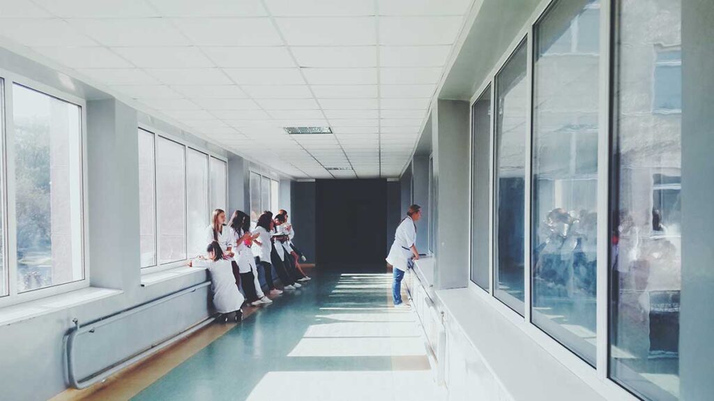 Healthcare professionals wait in the hallway of a hospital. Once they meet with their patients, they'll need to connect to a medical interpreter.