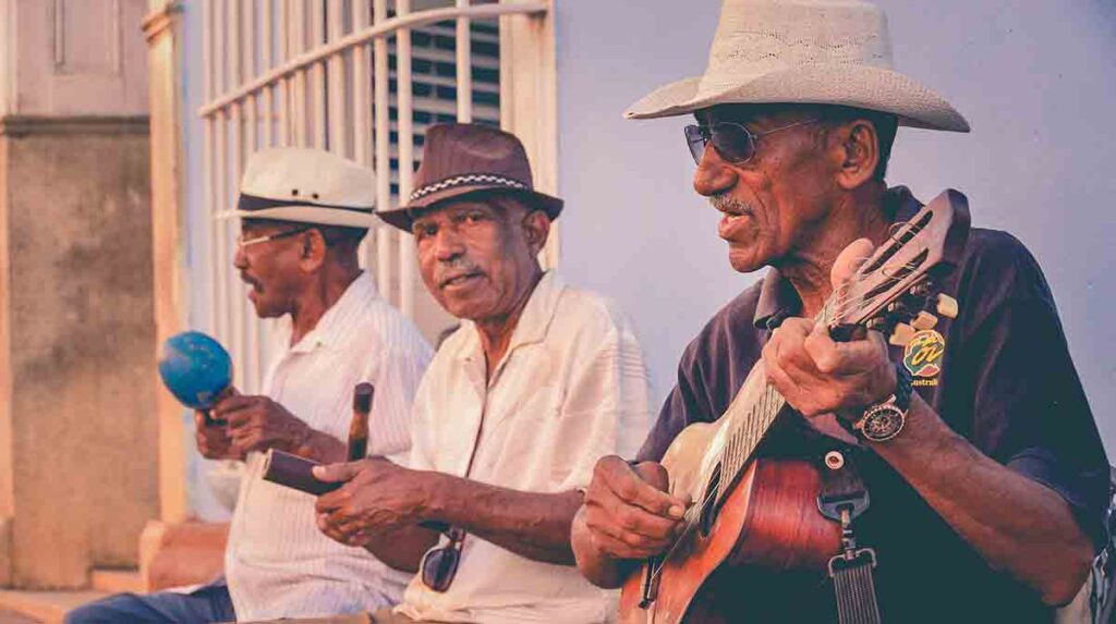 Three older Latino men playing instruments and singing 