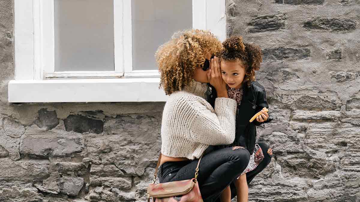 A mother whispers to her delighted child.