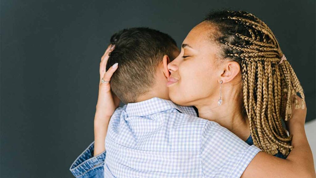 A compassionate mother smiles and hugs her child close while thinking of lessons learned as a parent and interpreter.