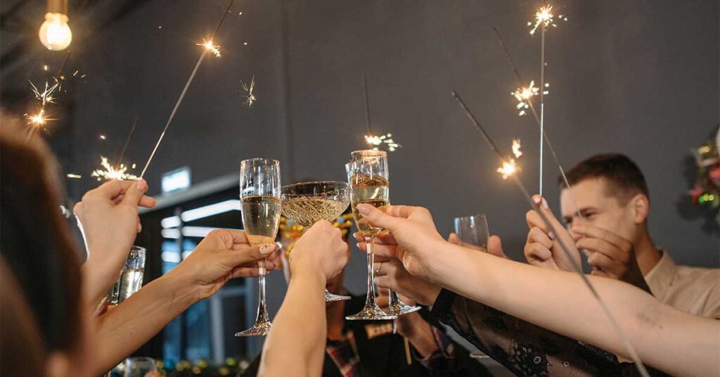 A group of friends toast to the New Year with glasses of champagne and sparklers.