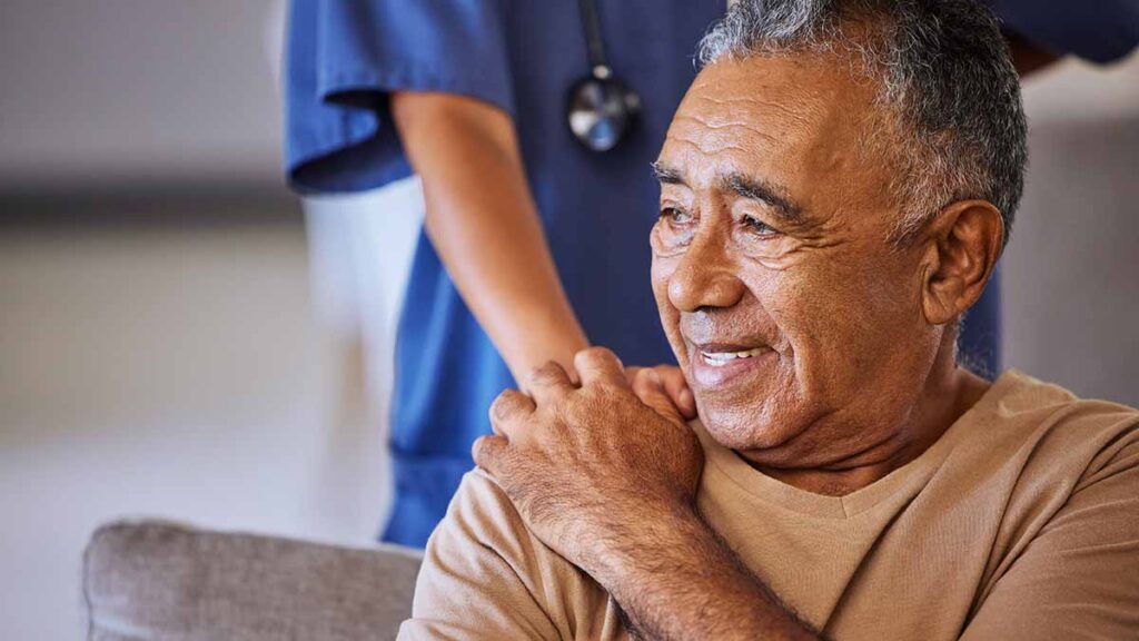 A nurse places a hand on a patient's shoulder after speaking with the help of a rare language interpreter.