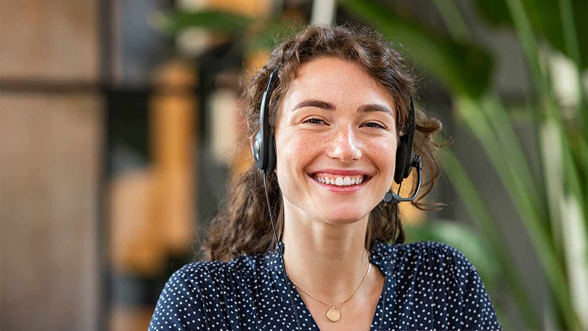 A smiling on-demand interpreter sits at a desk and waits for client to call.