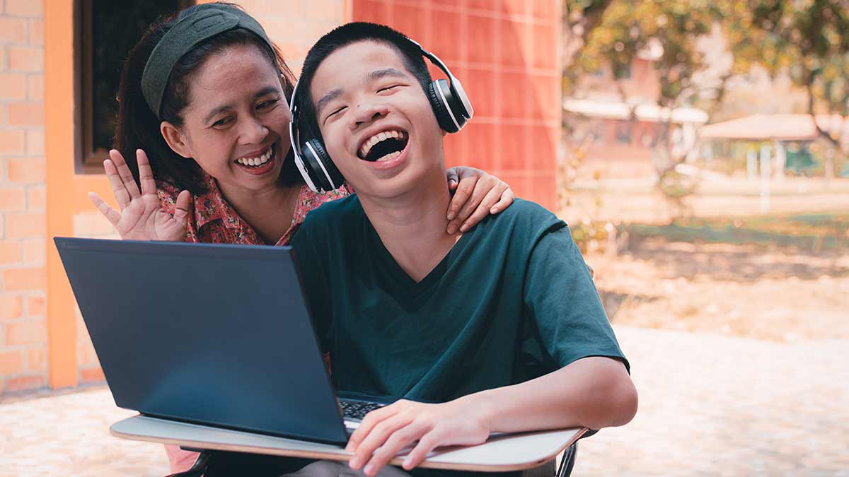 A smiling parent and child attend an IEP meeting through a video call.