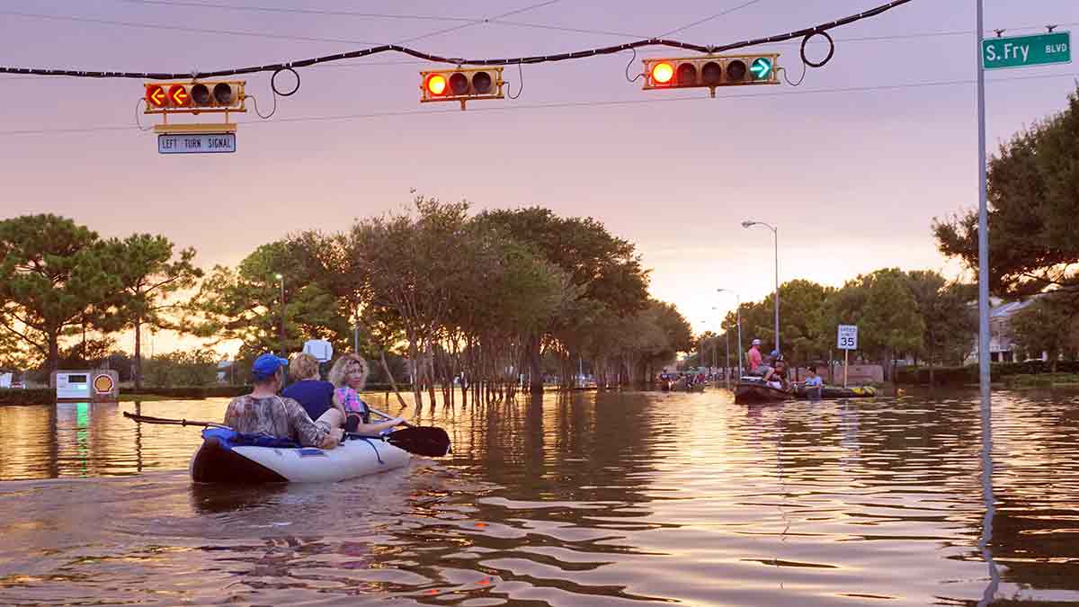 Following a natural disaster, people canoe through a street.