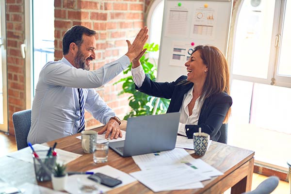 Two account representatives from language service providers high five after setting up white-label interpreting services.