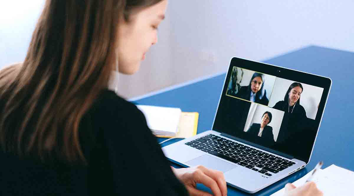 Woman on laptop communicating with two other woman via video.