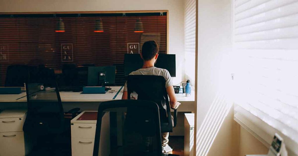 Male IT manager working at a computer in a room at a hospital.