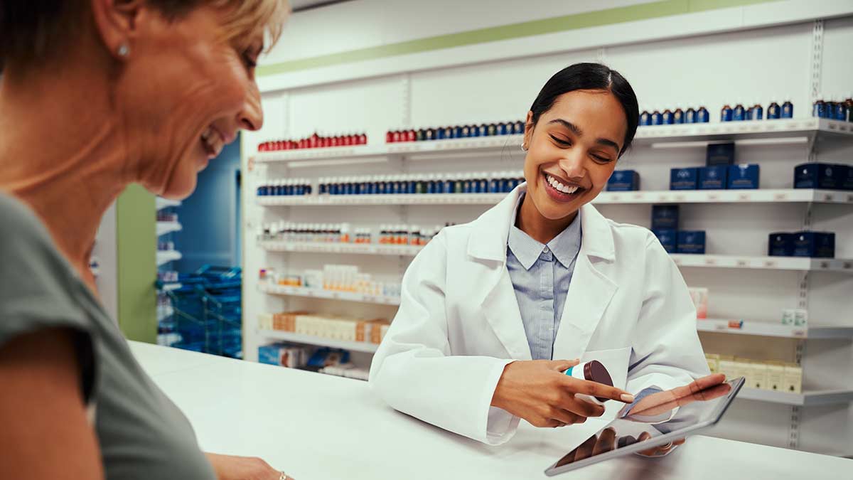 A pharmacist and patient look at an iPad together.