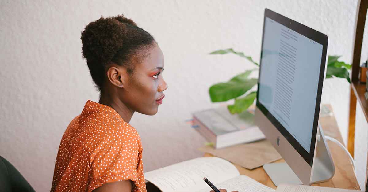 Female interpreter sitting at computer looking up resources to prepare for a remote interpreting session