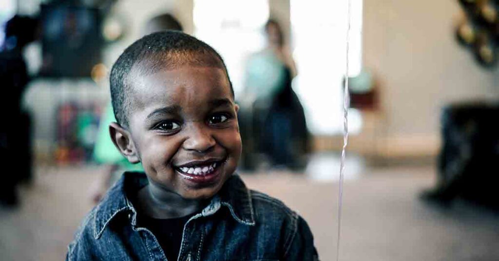 African American boy wearing a denim collared shirt and smiling