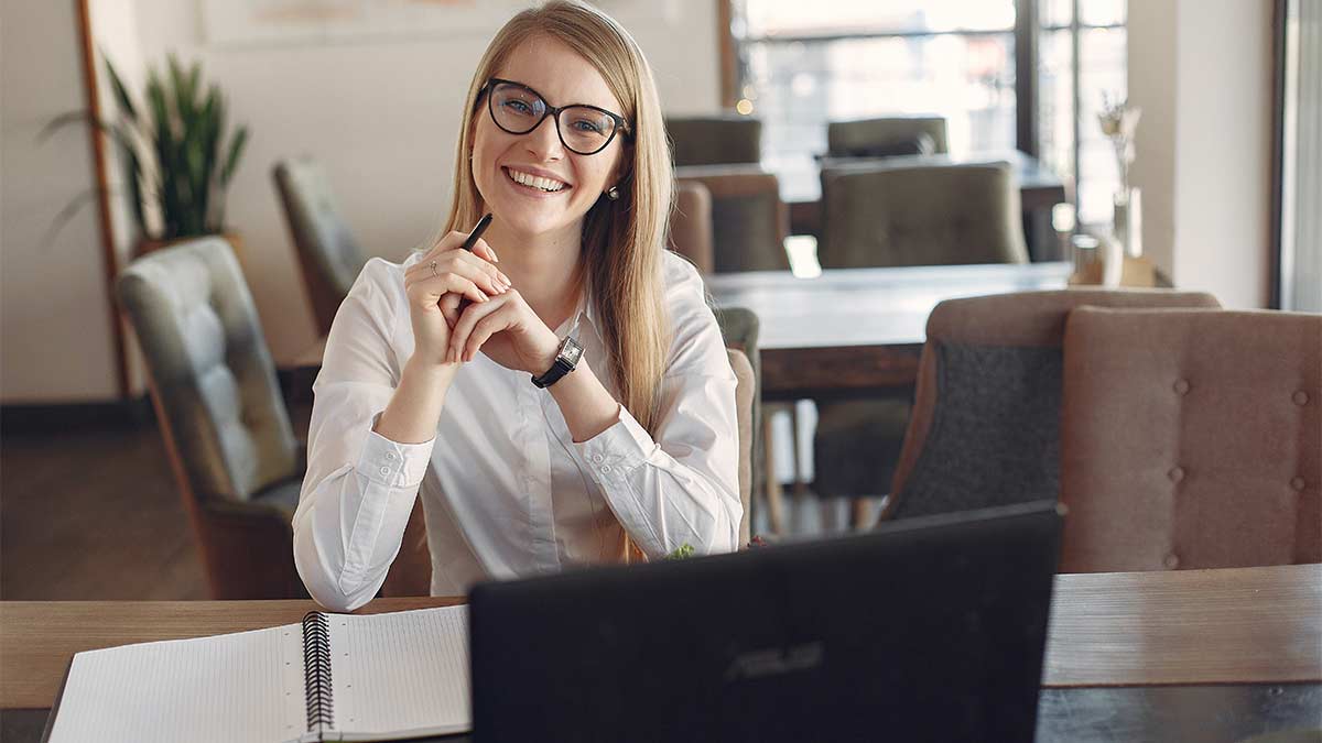 A professional translator looks up from a laptop with a smile.