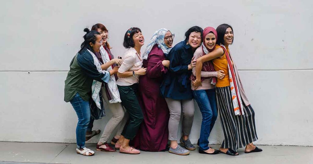 Group of seven women interpreters laughing and smiling against a white wall