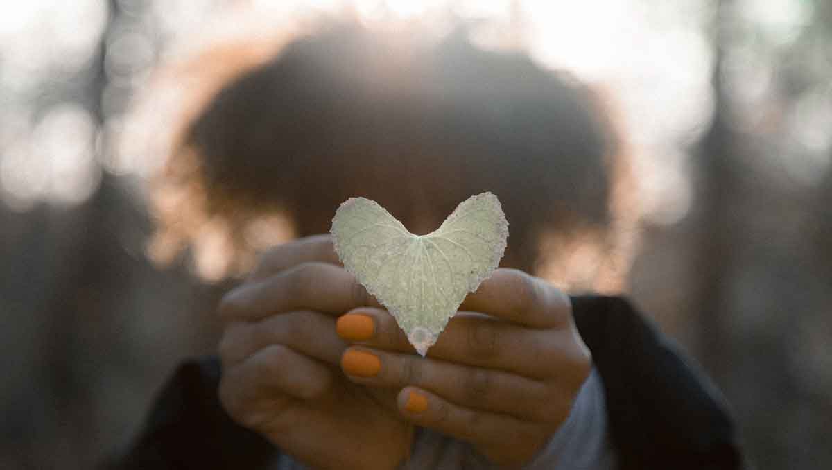 Woman holding a leaf shaped like a heart.