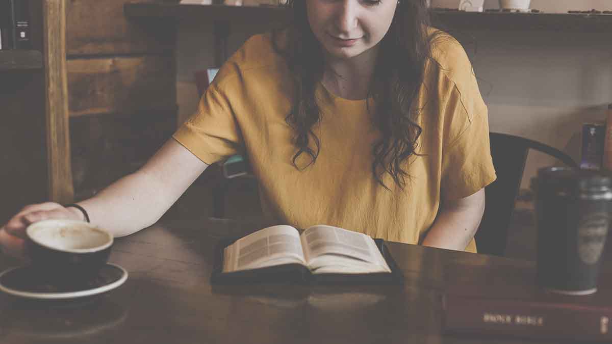 Woman sitting on chair in front of book with coffee