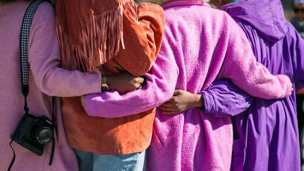 Four women who all live in the same community embrace