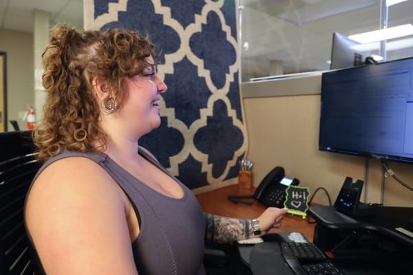 A customer service representative smiles at their computer screen.