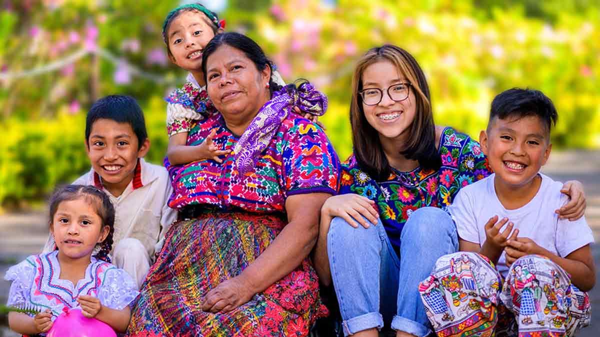 A family indigenous to Guatemala smiles together outside their home.