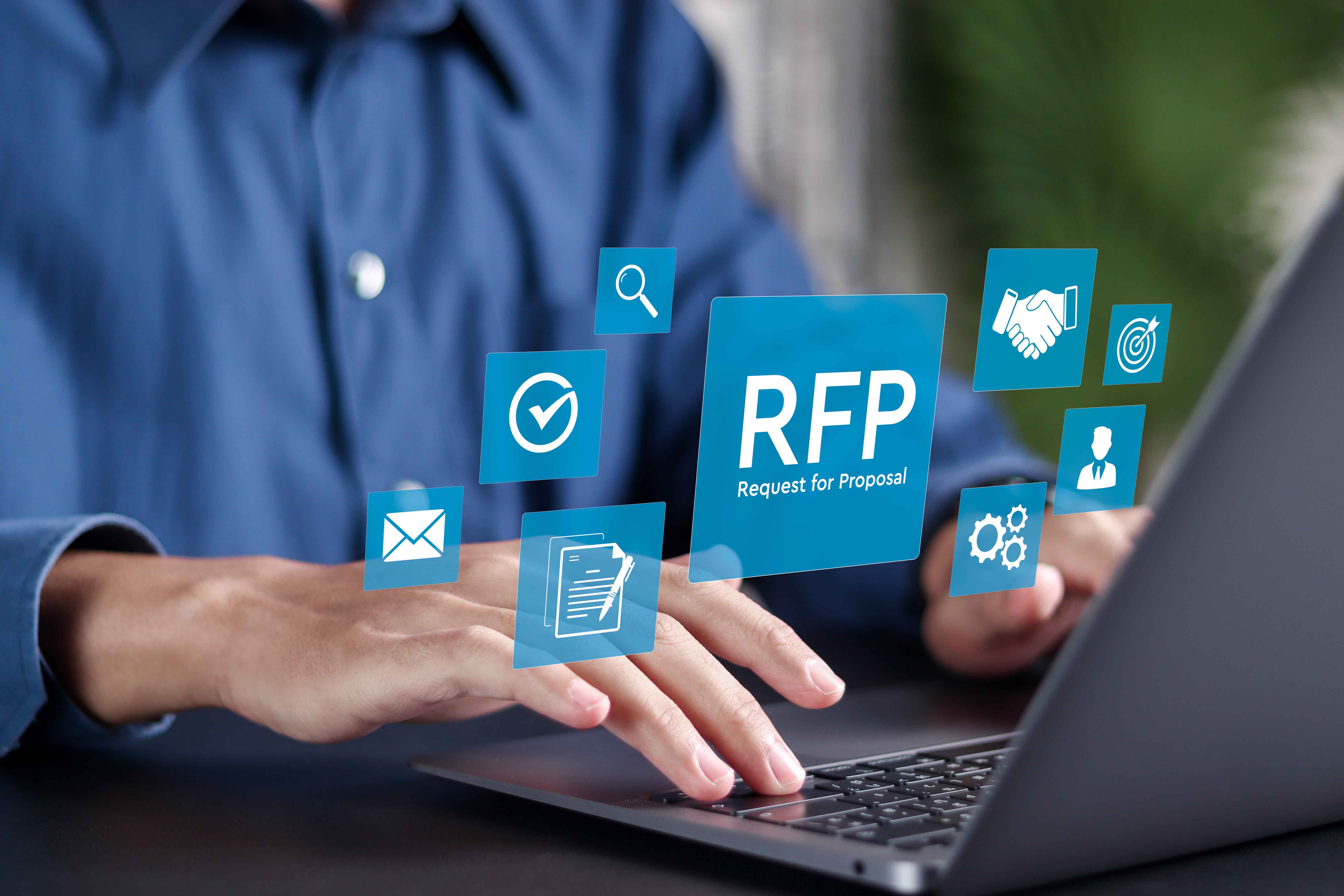 Businessman in blue shirt using laptop with Request for Proposal (RFP) icons on virtual screen.